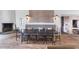 Open dining room featuring rustic wood floors, stone fireplace and custom upholstered bench seating at table at 7455 Old Rico Rd, Chattahoochee Hills, GA 30268
