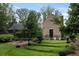 Charming brick home featuring a manicured lawn, lush greenery, and two Adirondack chairs at 7455 Old Rico Rd, Chattahoochee Hills, GA 30268