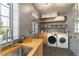 Well-organized laundry room featuring a sink, washer, dryer, shelving, wood countertop, and convenient storage at 7455 Old Rico Rd, Chattahoochee Hills, GA 30268