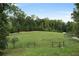 Sprawling green field enclosed by a wooden fence, surrounded by mature trees, offering privacy at 7455 Old Rico Rd, Chattahoochee Hills, GA 30268