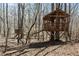 A whimsical treehouse featuring wooden construction, elevated platform and playful design in a wooded setting at 7455 Old Rico Rd, Chattahoochee Hills, GA 30268
