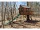 Charming treehouse with a slide, swing, and bridge, nestled among mature trees in a natural setting at 7455 Old Rico Rd, Chattahoochee Hills, GA 30268