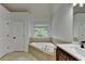 Bathroom featuring a soaking tub, dark cabinets, and a window at 3305 Suffolk Dr, Cumming, GA 30041