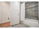 Modern bathroom with tub, shower, and gray wood-look tile accent wall and wood floors at 1552 Newton Se Ave, Atlanta, GA 30316