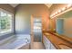Bright bathroom featuring double sinks, a large bathtub, and an exterior window at 2037 Castlemaine Circle, Woodstock, GA 30189