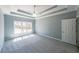 A spacious bedroom features plush gray carpeting, a ceiling fan, a large window, and tray ceiling at 2037 Castlemaine Circle, Woodstock, GA 30189