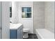 Bathroom with blue vanity, toilet, tub, gray flooring and tile walls at 1894 Evans Sw Dr, Atlanta, GA 30310