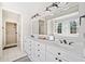 Elegant bathroom featuring double sinks, white cabinetry, dark fixtures, and a large mirror with decorative lighting at 332 William Falls Dr, Canton, GA 30114