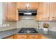 Close-up of granite countertops, tile backsplash, gas stovetop and wood cabinets in this spacious kitchen at 332 Williamfalls Dr, Canton, GA 30114