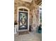 Stylish front door framed by stone with potted plants, doormat, and a decorative wreath at 78 Cuthbert Ln Ne, Acworth, GA 30101