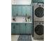 Modern laundry room with side-by-side washer and dryer, and custom teal cabinetry at 78 Cuthbert Ln Ne, Acworth, GA 30101