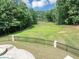 Lush backyard with a view of the lake, surrounded by trees and a black metal fence at 4233 Sandstone Shores Dr, Stonecrest, GA 30038