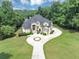 Elegant home featuring a circular driveway, manicured lawn, and mature trees at 4233 Sandstone Shores Dr, Stonecrest, GA 30038