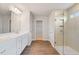 Stylish bathroom featuring dual vanities, wood-look floors, and a glass-enclosed shower with tiled walls at 6945 Melody Ridge Rd, Buford, GA 30518