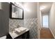 Stylish powder room featuring a white vessel sink, geometric tile, gold fixtures, and adjacent hallway view at 2436 Planters Mill Way, Conyers, GA 30012