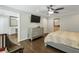 Bedroom featuring wood floors, a ceiling fan, and a dresser with a large TV above it at 4970 Lakeland Woods Ct, Atlanta, GA 30338