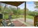 Covered patio looking out to the large backyard with mature trees and a wooden fence at 345 Lambeth Dr, Hiram, GA 30141