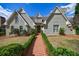 Attractive home featuring a brick facade, arched windows, a dormer, and a brick walkway lined with manicured hedges at 5 Coventry Close, Avondale Estates, GA 30002