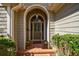Charming front entrance with an arched doorway, decorative glass door, and brick walkway lined with green shrubs at 5 Coventry Close, Avondale Estates, GA 30002