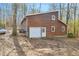 Rear view of home featuring a garage, white doors and wood facade, with trees in background at 279 Alex St, Canton, GA 30114