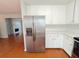 Stainless steel refrigerator in a modern kitchen with wood floors and view to Gathering room at 3520 Newberry Ln, Douglasville, GA 30135