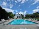 Large community pool with plenty of lounge chairs under a sunny sky, surrounded by lush greenery at 7640 Harbour Walk, Cumming, GA 30041