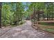 Long driveway leading to the home through a lush, wooded landscape with a charming fence at 7640 Harbour Walk, Cumming, GA 30041