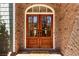 Elegant double front doors with glass panes, framed by a brick facade and a welcoming doormat at 7640 Harbour Walk, Cumming, GA 30041