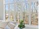 Close-up of a large window overlooking a serene wooded landscape with a comfortable sofa nearby at 7640 Harbour Walk, Cumming, GA 30041