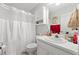 Bright bathroom with a white vanity, toilet, and shower with white curtain, and ample storage in the mirrored cabinet at 1152 Strath Clyde Way, Mcdonough, GA 30253