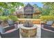 Stunning backyard with stone fire pit, patio seating, and multi-level deck overlooking lush greenery at 3270 New University Trl, Cumming, GA 30041