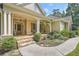 Charming front porch featuring a stone walkway, hanging plants, and a cozy seating area at 3270 New University Trl, Cumming, GA 30041