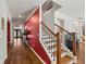 View of the foyer featuring a staircase with wood treads, a red accent wall and hardwood floors at 3316 Quarter Horse Ln, Conyers, GA 30013