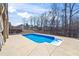 Backyard swimming pool with surrounding concrete patio, and black metal fence with trees in the background at 3316 Quarter Horse Ln, Conyers, GA 30013