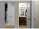 Hallway view of vanity with mirror and lighting; two paneled doors are on the left at 6545 Muirfield Pt, Fairburn, GA 30213