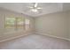 Neutral bedroom features a tray ceiling with fan, large windows with blinds, and plush carpeting at 145 Sunset Ln, Woodstock, GA 30189
