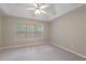 Neutral bedroom features a tray ceiling with fan, large windows with blinds, and plush carpeting at 145 Sunset Ln, Woodstock, GA 30189