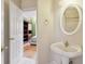 Powder room with a white oval mirror, pedestal sink, and door to the bedroom at 918 Edgewater Dr, Loganville, GA 30052