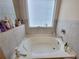 Bright bathroom featuring a large soaking tub with tile surround and a window at 1125 Campbell Pine Trl, Lawrenceville, GA 30045