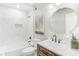 Well-lit bathroom featuring modern fixtures, tiled shower, and a round mirror above a stylish vanity for a contemporary design at 232 Westminster Ne Dr, Atlanta, GA 30309