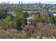 Aerial view showcasing a house amidst lush greenery, with a city skyline in the distance, hinting at urban convenience at 827 Derrydown Way, Decatur, GA 30030