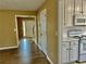 Hallway featuring wood-look floors and neutral walls leading to a well-lit foyer and kitchen with white appliances at 2703 Regal Cir, Conyers, GA 30012