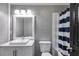 Bathroom featuring a modern vanity, sink, toilet, and bathtub with a blue striped shower curtain at 9760 Greenside Way, Douglasville, GA 30135