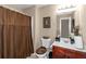 Traditional bathroom with a cherry vanity, framed mirror, shower with patterned curtain, and tile floor at 7881 Wilkerson Ln, Palmetto, GA 30268