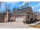 Side view of a brick house with a large garage and driveway, with landscaping and a partial deck view at 7881 Wilkerson Ln, Palmetto, GA 30268