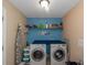 Well-lit laundry room with washer, dryer, folding counter, shelf, laundry themed wall décor, and an ironing board at 7881 Wilkerson Ln, Palmetto, GA 30268