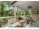 Covered outdoor patio featuring comfortable seating, dining area, ceiling fan, and view of lush greenery at 4827 Basingstoke Dr, Suwanee, GA 30024