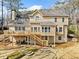 Back exterior view of a tan home with a spacious deck, stone patio, stairs, and lush greenery in a serene backyard setting at 1904 Rosewood Ln, Woodstock, GA 30189