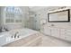 Bathroom with a large tub, glass shower, double sink vanity with quartz countertops, and marble tile floors at 1904 Rosewood Ln, Woodstock, GA 30189