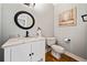 This half bathroom features a white vanity with marble top, a round mirror and wood flooring at 1904 Rosewood Ln, Woodstock, GA 30189